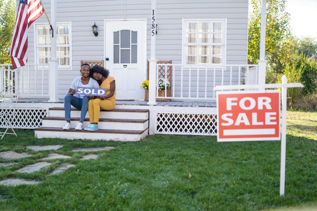 Happy homeowners with "Sold" sign